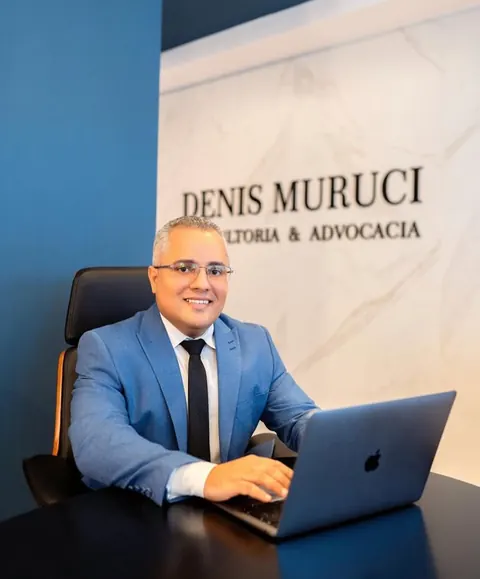 Denis Muruci na recepção, diante do letreiro do escritório